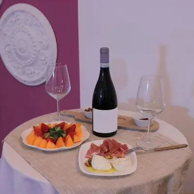 a table with two plates of food and a bottle of wine at Il Rosone Luxury B&B in Palermo
