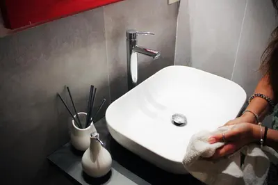a woman standing next to a white sink in a bathroom at Palazzo delle Logge in Palermo
