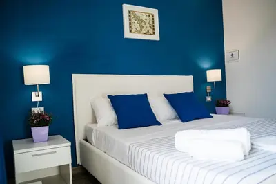 a blue bedroom with a white bed with blue walls at Le Due Sicilie B&B in Lascari