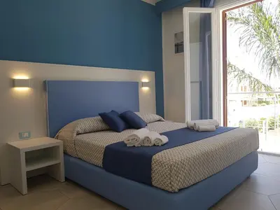 a blue bedroom with a bed with towels on it at B&B Aloe Comfort Rooms in San Vito lo Capo