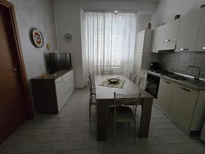 a kitchen with a table and chairs and a kitchen with white cabinets at casa francesca in Castellammare del Golfo