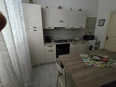 a kitchen with white cabinets and a wooden table with a tableablish at casa francesca in Castellammare del Golfo
