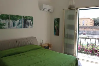 a bedroom with a green bed and a large window at Le Torri dell'acqua in Palermo