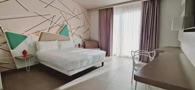 a bedroom with a white bed and a large window at Saracen Sands Hotel & Congress Centre - Palermo in Isola delle Femmine