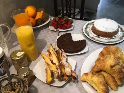 a table with plates of pastries and cake and orange juice at Kurò in Palermo