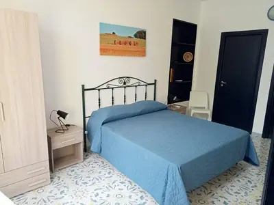 a bedroom with a bed with a blue comforter at Scopelos in Scopello