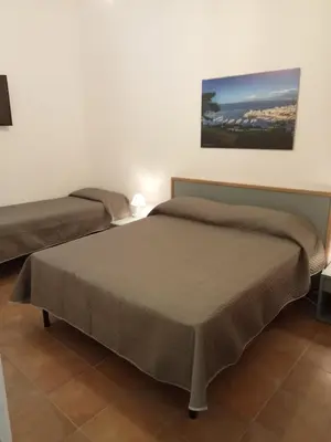 two beds in a room with a painting on the wall at Scopelos in Scopello