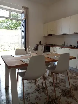 a kitchen with a wooden table with chairs and a dining room at Scopelos in Scopello