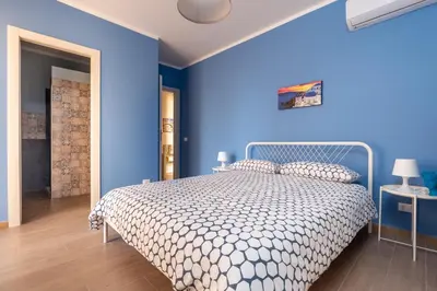a blue bedroom with a bed and a blue wall at B&B Medusa in Santa Flavia