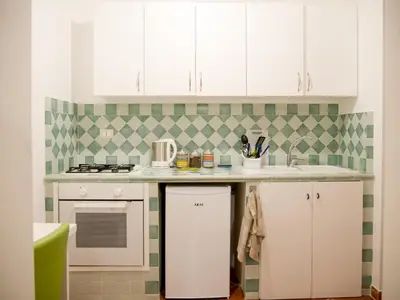 a kitchen with white cabinets and green and white tiles at Madinah apartments in Palermo