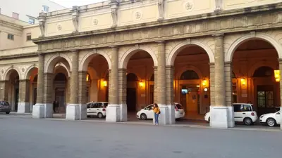 a woman standing in front of a building with parked cars at Alla Casetta in Palermo