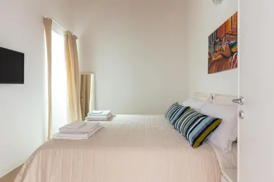 a white bedroom with a bed with pillows and a window at Il Sonno dei Giusti Apartment by DomuSicily in Palermo