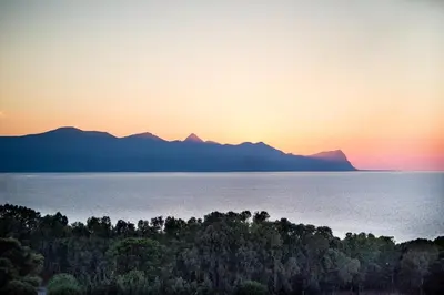 a sunset over the water with mountains in the background at Petruso Resort e SPA in Balestrate