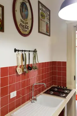 a kitchen with red tiles on the wall and a sink at dallo Zio Totò in Palermo