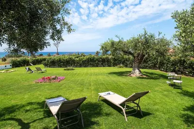 a lawn with chairs and a table and a tree at Nettuno in Cefalù