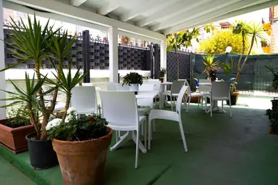 a patio with white chairs and tables and plants at Kunesias B&B in Cinisi