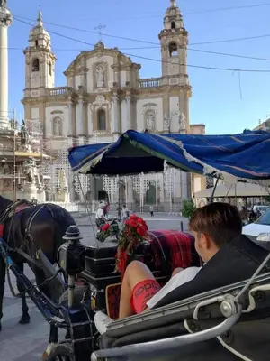a man and a woman riding in a horse drawn carriage at La Casetta Di Marta ai Quattro Canti in Palermo