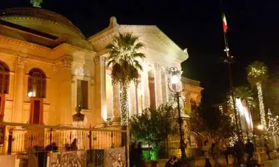 a building with a palm tree in front of it at La Casetta Di Marta ai Quattro Canti in Palermo