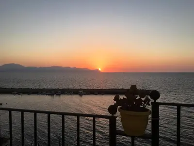 a sunset over the water with a potted plant at Casa vacanze Al porticciolo romantico in Trappeto
