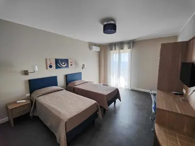 a hotel room with two beds and a television at Dependance La Mouette in Termini Imerese