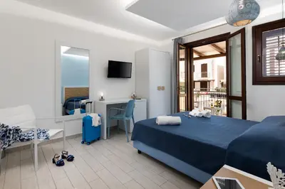 a bedroom with a blue bed and a living room at B&B Reset confort & relax in San Vito lo Capo