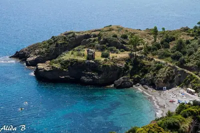 an island in the ocean with people on the beach at Hotel Torre Normanna in Altavilla Milicia