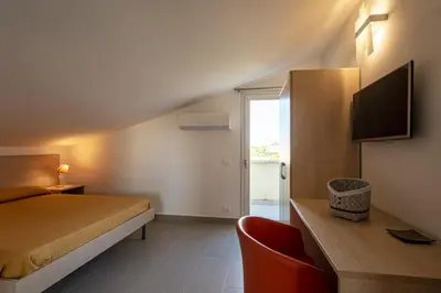 a bedroom with a bed and a desk and a tv at Borgo Aranci - Appartamento in Villa Rosa - 16B in Castellammare del Golfo