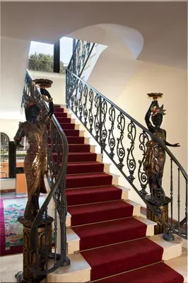 a staircase with a statue of two women on the railing at Hotel Giardino Inglese in Palermo