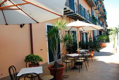 an outdoor patio with tables and chairs and umbrellas at Hotel Giardino Inglese in Palermo