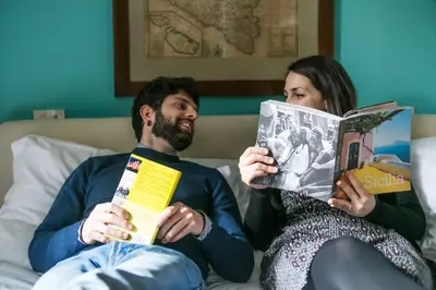 a man and woman sitting on a bed reading books at Ai Vicerè in Palermo