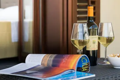 a bottle of wine and a book on a table with wine glasses at La Dimora del Pescatore in San Vito lo Capo