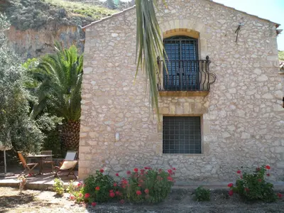 a stone building with a balcony and flowers at the ancient sicilian house near zingaro reserve Scopello in Scopello