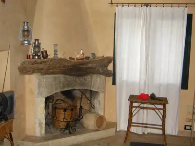 a living room with a fireplace and a window at the ancient sicilian house near zingaro reserve Scopello in Scopello