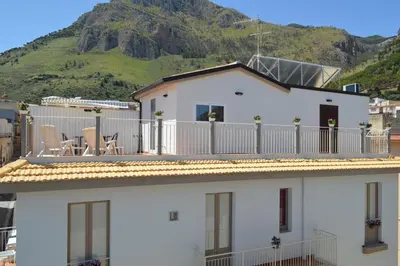 a white house with chairs on a balcony with a mountain at Le Sette Meraviglie in Castellammare del Golfo