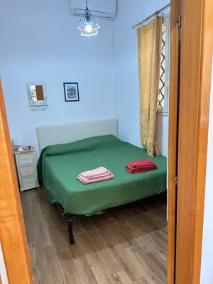 a small green bed in a room with a window at House Cefalù 1915 in Lascari