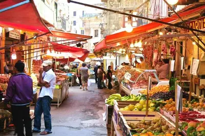 a group of people walking around a market with fruits and vegetables at Casa Siciliabedda in Capaci