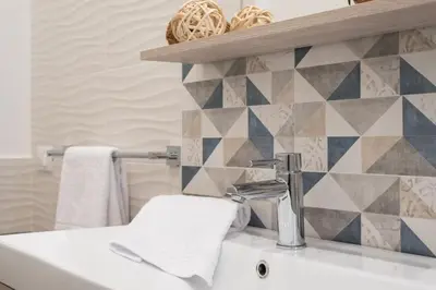 a bathroom with a sink and a tile wall at Rugiada Home Castellammare del Golfo in Castellammare del Golfo