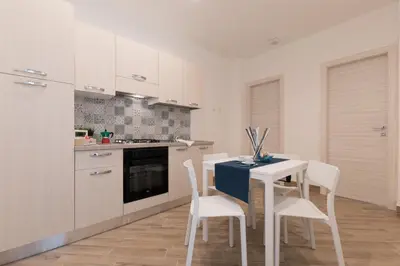 a kitchen with a white table and white chairs at Rugiada Home Castellammare del Golfo in Castellammare del Golfo