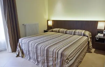 a hotel room with a bed with a striped blanket at BB 10 Serpotta - Palazzo Riolo & Restaurant in Palermo