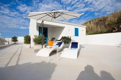 a group of chairs and an umbrella on a patio at Marina Beach Resort by Le Dhome Sicily in Balestrate