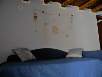 a blue couch against a white wall with some items on it at A Vanedda in Termini Imerese