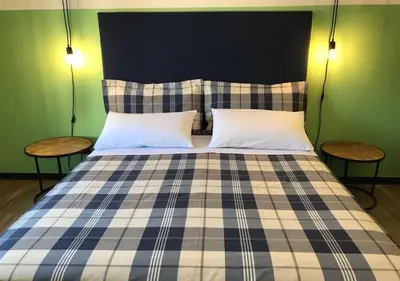 a bed with a blue and white plaid blanket and two tables at NA' SCICCHERIA HOME in Castellammare del Golfo
