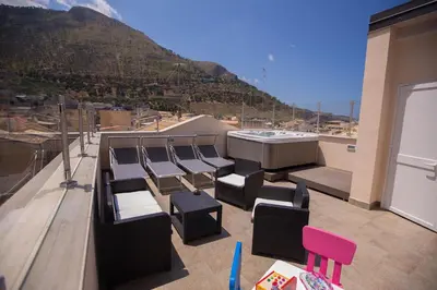 a balcony with chairs and a hot tub and a mountain at Sciabika Home - Edificio Eolie in Castellammare del Golfo