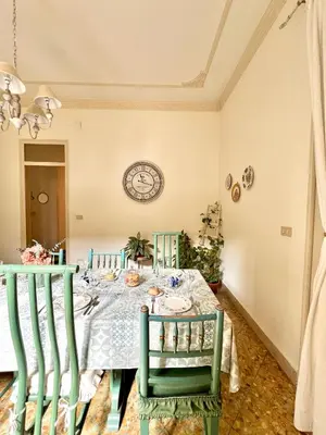 a dining room with a table with green chairs and a clock at Casa Jolanda B&B in Palermo