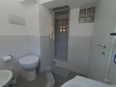 a white bathroom with a toilet and a shower at la petit maison in Palermo