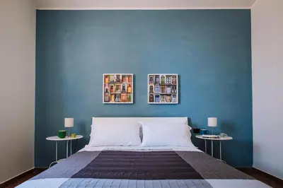 a bedroom with a blue wall with a bed and two tables at Villa Zabbara Capo Zafferano in Bagheria