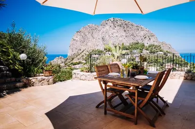 a table with chairs and an umbrella on a patio at Villa Zabbara Capo Zafferano in Bagheria