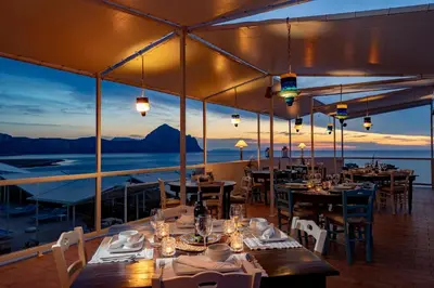 a restaurant with tables and chairs and a view of the ocean at Hotel Pocho in San Vito lo Capo