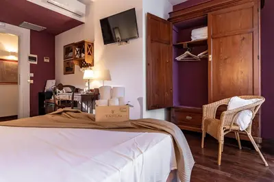 a bedroom with purple walls and a bed and a chair at Hotel Pocho in San Vito lo Capo