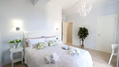 a white bedroom with a bed with towels on it at La Via dell'Acqua in Macari